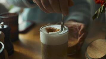 Close-up of male hands pours sugar into coffee. Adding sweetener or fructose to beverage. Hot art Latte Coffee in a cup on wooden table and Coffee shop blur background video