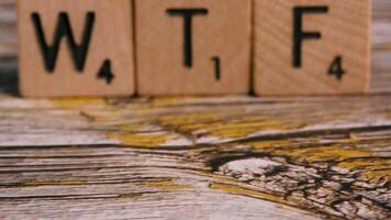 Dolly move on block letters WTF over wood background for creative message video