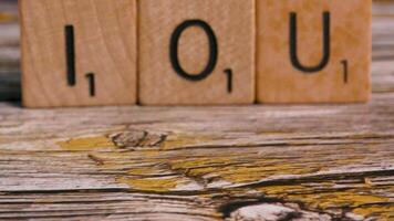 Dolly move on block letters IOU over wood background for debt financial concept video