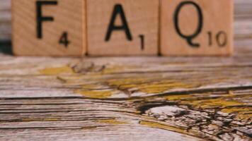 Dolly move on block letters FAQ over wood background help concept video