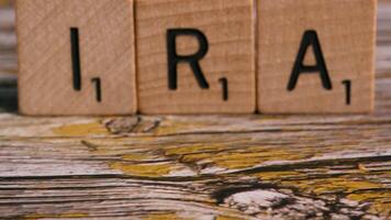 Dolly move on block letters IRA over wood background for financial video