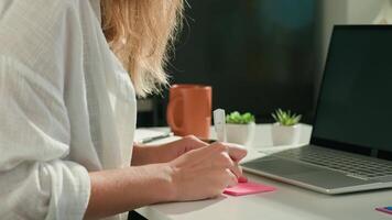 Woman is using sticky notes on her laptop screen to organize her work while working remotely from home. Concept of planning and task management in office work video
