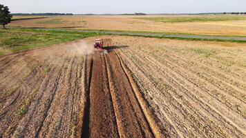 Red tractor working in agricultural field, cultivating and plowing dry soil, aerial view. Agribusiness concept. Small farming concept video
