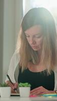 Person is sketching in notebook while working remotely at desk with laptop. Freelance work at home office. Graphic designer drawing sketch video