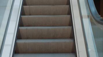 Modern escalator with glass railings leading upwards in public space. Infrastructure for urban mobility video