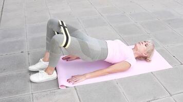 Woman is doing a Glute Bridge with a Resistance Band as part of her Fitness Training routine video