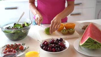 Anonymous female cutting lime on table with cherries and watermelon video