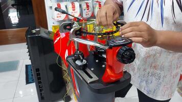 Kediri, Indonesia on October 12, 2024. A man is stringing a badminton racket using a red stringing machine. Badminton stringing machine. video