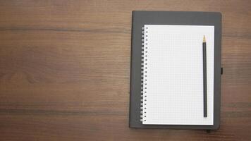 Notebook with pencil on wooden table top view photo