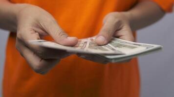 close-up of a woman's hand counting a stack of US hundred dollar bills. a businessman counting cash. concepts of investment, money exchange, bribery, or corruption. selective focus. video