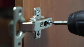 A man uses a drill to install a hinge from a cabinet door. video