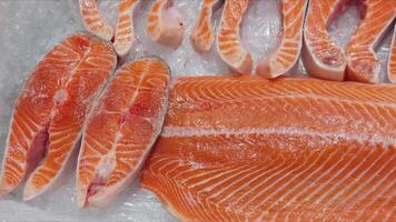 There are chopped pieces of red fish on the display case with ice. video