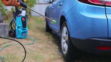 Car washing with high-pressure water. A man in gloves washes a car in the backyard of his house. video
