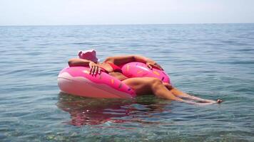 Woman Inflatable Ring Sea Relaxing. A young woman floats on an inflatable ring in the sea, enjoying a relaxing day at the beach. video