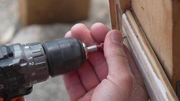A man hands using a power tool fastens a board with a screw. Slow motion video