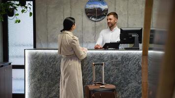 Businesswoman at the reception of a hotel checking in. Guest getting key card in hotel video