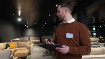 Sales assistant making notes in clipboard in furniture store video