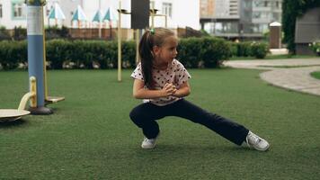 Young girl practicing squats at a playground on a sunny day video