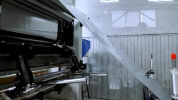 In factory that manufactures metal products, metal sheet is automatically stretched on roll by specialized machine for transportation. video