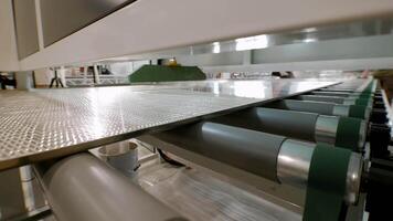 Process applying adhesive to large aluminum sheets of metal in fully automated manner, utilizing specialized machinery and equipment for continuous production. video