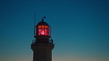 Rotating bright red light located at the summit of a large lighthouse assists mariners in navigation and alerts them to potential hazards. Slow motion video