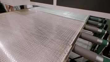 Metal sheet is transported on conveyor belt, which is coated with fresh adhesive, in fully automated process for manufacturing of furniture items. video