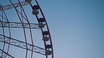 The view of the Ferris wheel's cabins, sparkling with bright lights against the clear blue sky in the evening. video