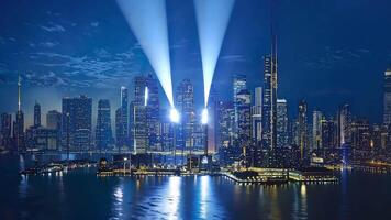 A stunning city skyline illuminated by powerful lights against a twilight sky, reflecting on calm waters. video
