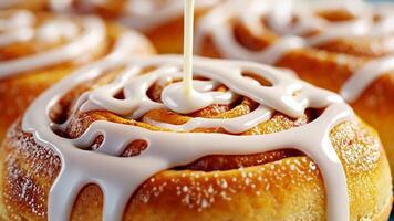 A close up of freshly baked cinnamon rolls being drizzled with icing, perfect for Christmas or brunch concepts video