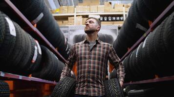 A man walking in a tire store with two new tires for car video