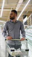 A man with shopping cart on escalator in a hardware store. Vertical video