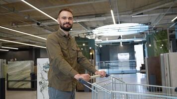 Portrait of handsome man with trolley at luxury tiles shop video