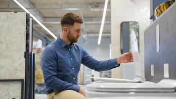 Young man choosing bathroom toilet bowl and utensils for his home video