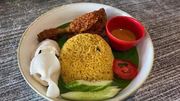 Nasi goreng with chicken rendang. Fried rice asian popular food served with cucumber slices and crackers. video