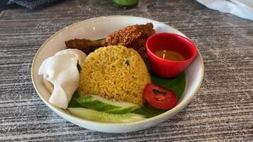 Nasi goreng with chicken rendang. Fried rice asian popular food served with cucumber slices and crackers. video