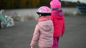 Two Little Girls Learn to Ride a Bicycle by the Lake on an Autumn Day video
