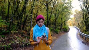 Woman with Backpack Using Smartphone, Hiking In The Forest And Typing Message On Smartphone. Solo female hiker using smart phone. Female hiker takes smart phone pic of mountains and forest. video