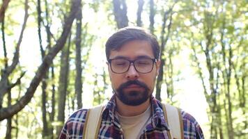 Standing alone in the forest in the open air against a forest background. close-up portrait face. Traveling Concept People in Nature. Hiker Journey in Wildlife video