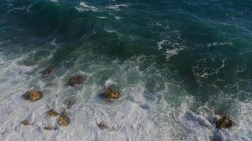 Breathtaking top aerial slow motion view of azure ocean and giant waves crashing at rocky cliff with splashing and white foam. video
