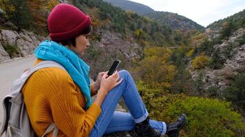 Woman with Backpack Using Smartphone, Hiking In The Mountains And Typing Message On Smartphone. Solo female hiker using smart phone. Female hiker takes smart phone pic of mountains video