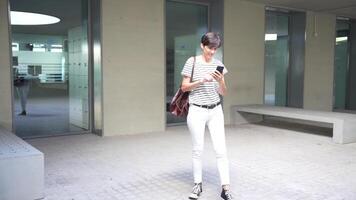A Young Individual Strolling While Using a Smartphone Inside a Contemporary Building Space video