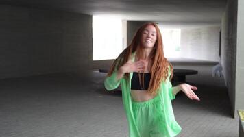 A woman energetically dances in green urban tunnel, expressing joy with dynamic choreography video