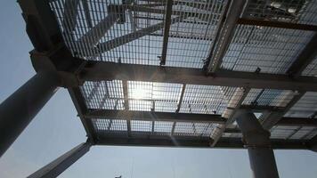 Industrial Metal Grate Structure with Sunlight Shining Through. Low-angle view of an industrial metal grate structure, with sunlight shining through the gaps. video