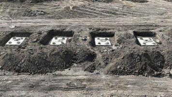 costruzione luogo fondamenta nel appena scavata suolo. un' costruzione luogo mostrando parecchi rettangolare fondazione pozzi scavata in il suolo, con rinforzata acciaio barre emergente a partire dal il calcestruzzo basi. video