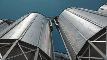 Close-up view of modern grain silos from below. A striking low-angle shot of modern grain silos, towering against a clear blue sky. video