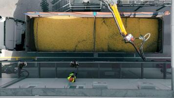 Overhead view of grain being loaded into a truck at a facility. A top-down view of grain being loaded into a large truck at an agricultural processing facility. video