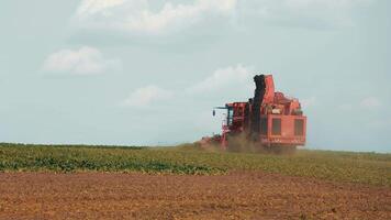 Large agricultural machine harvesting crops in a field. A large red agricultural machine harvesting crops in a vast open field. video