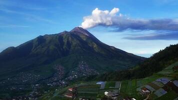Drone Movement Shows the Beauty and Majesty of the Smoking Mount Merapi. The towering mountain is surrounded by lush green valleys and scattered villages at its base. video