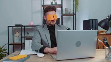 Inefficient tired lazy businessman working sleeping on laptop computer with eyes stickers on face video