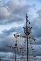 Masts, sail yards with lowered sails, and rigging of a sailing ship against a sunset sky photo